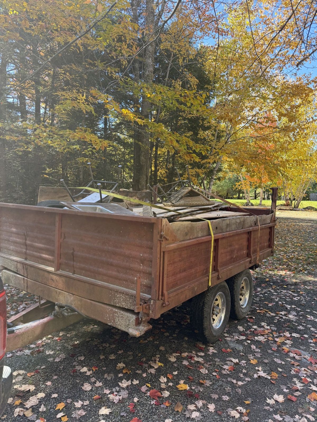 A trailer loaded with wood, chairs and mixed debris.